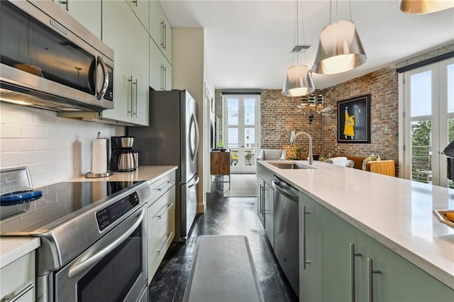 kitchen with brick wall, appliances with stainless steel finishes, a healthy amount of sunlight, and sink