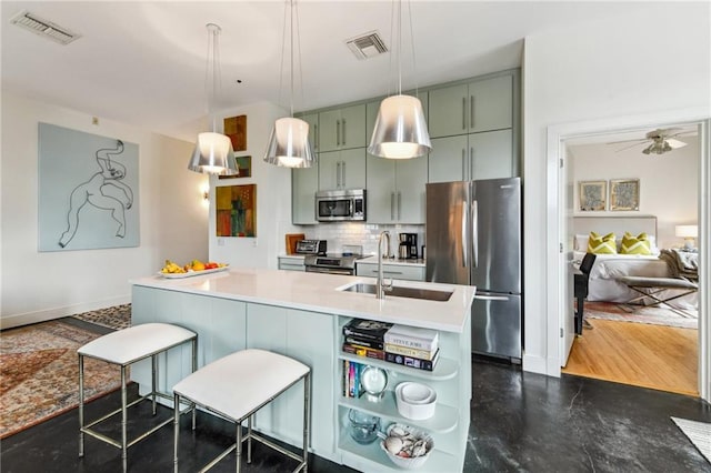 kitchen with stainless steel appliances, ceiling fan, green cabinetry, a kitchen bar, and sink