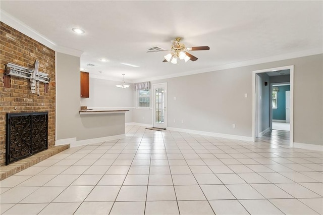 unfurnished living room with ceiling fan with notable chandelier, a brick fireplace, ornamental molding, and light tile patterned floors