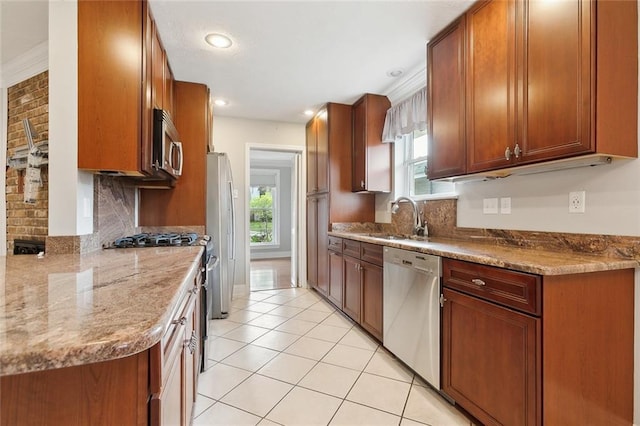 kitchen with sink, stainless steel appliances, light tile patterned flooring, and light stone counters