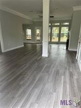 unfurnished living room featuring dark wood-type flooring and ornamental molding