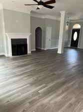 unfurnished living room featuring a fireplace, ceiling fan, crown molding, and dark hardwood / wood-style flooring