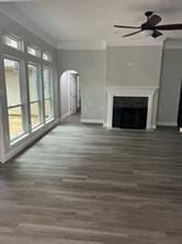 unfurnished living room featuring ceiling fan, crown molding, and dark hardwood / wood-style floors