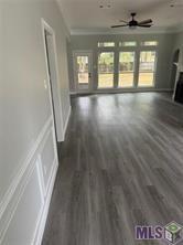 unfurnished living room featuring ceiling fan, ornamental molding, and dark hardwood / wood-style floors