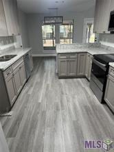 kitchen featuring kitchen peninsula, stainless steel appliances, light wood-type flooring, and sink