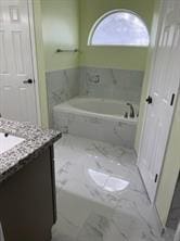 bathroom featuring vanity and tiled bath