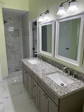 bathroom with a tile shower and vanity