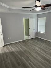 unfurnished bedroom with dark wood-type flooring, a raised ceiling, and ceiling fan