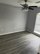 empty room with dark wood-type flooring and ceiling fan