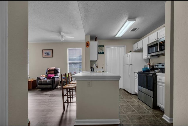 kitchen with appliances with stainless steel finishes, kitchen peninsula, a kitchen bar, sink, and white cabinetry