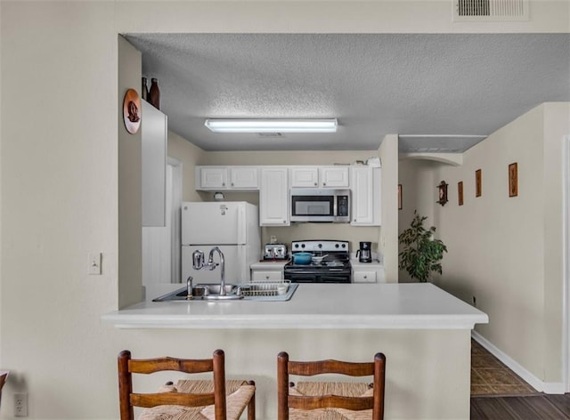 kitchen with sink, white cabinetry, a textured ceiling, kitchen peninsula, and appliances with stainless steel finishes