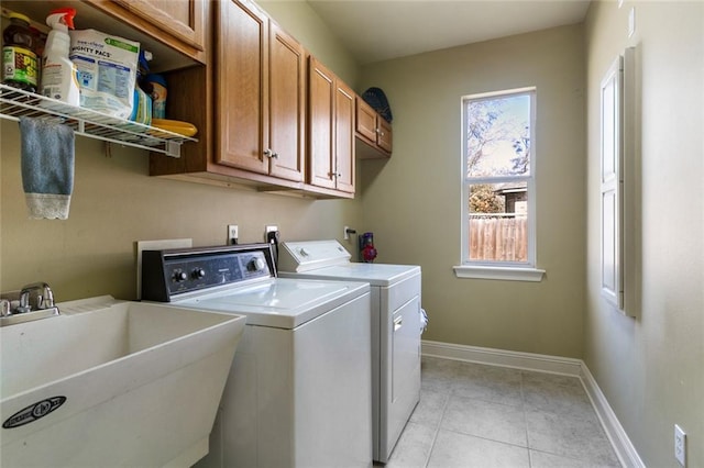 laundry area featuring cabinets, light tile patterned floors, washer and clothes dryer, and sink