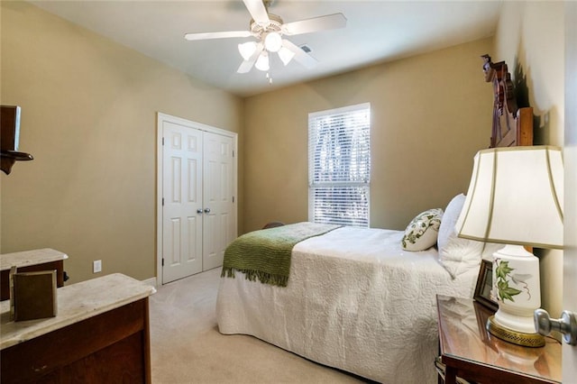 bedroom with light colored carpet, ceiling fan, and a closet