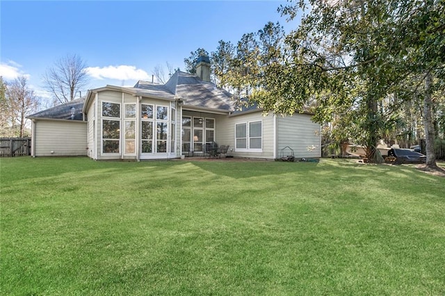 rear view of house with a yard and a sunroom