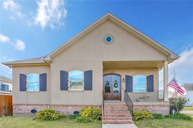 view of front of home with french doors, covered porch, and a front lawn