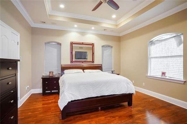 bedroom featuring hardwood / wood-style flooring, ceiling fan, a tray ceiling, and ornamental molding