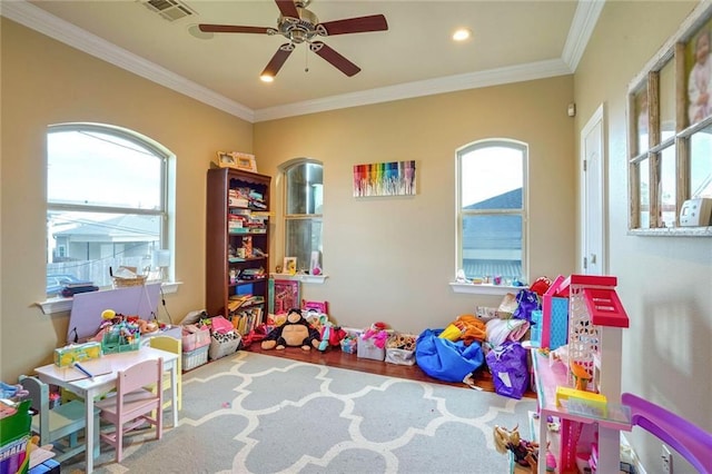 rec room with hardwood / wood-style flooring, ceiling fan, crown molding, and a healthy amount of sunlight