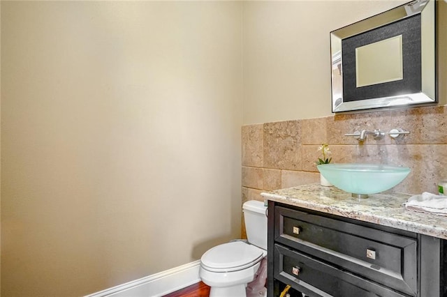 bathroom with toilet, vanity, hardwood / wood-style flooring, and tasteful backsplash