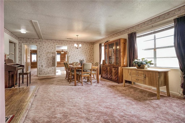 dining space with a textured ceiling, carpet floors, and a chandelier