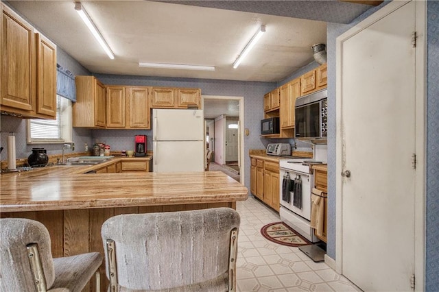 kitchen featuring sink, white appliances, a kitchen breakfast bar, kitchen peninsula, and butcher block countertops