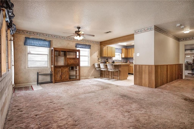 unfurnished living room featuring a textured ceiling, ceiling fan, and a wealth of natural light