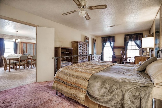 bedroom featuring ceiling fan with notable chandelier, a textured ceiling, carpet flooring, and multiple windows