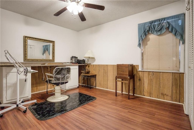 sitting room with a textured ceiling, wood walls, ceiling fan, and hardwood / wood-style floors