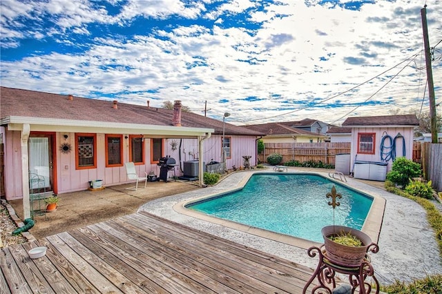 view of pool with grilling area, central AC, and a wooden deck