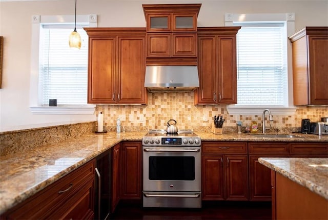 kitchen featuring sink, light stone counters, stainless steel electric range, hanging light fixtures, and wall chimney range hood