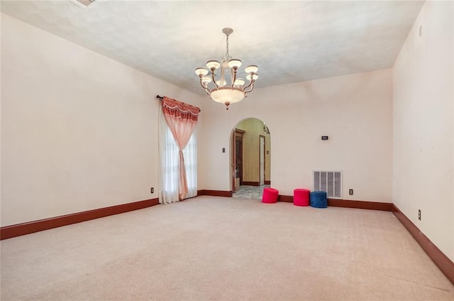 spare room with carpet flooring and a chandelier