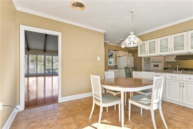 dining room featuring crown molding, light tile patterned floors, a chandelier, and sink