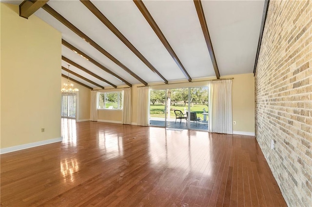 unfurnished living room with wood-type flooring, an inviting chandelier, and vaulted ceiling with beams