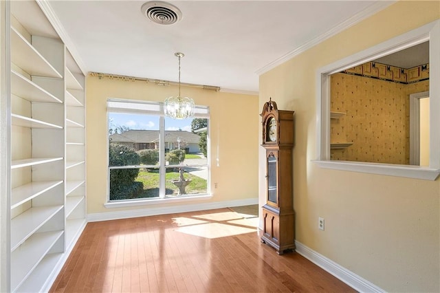 unfurnished dining area featuring hardwood / wood-style flooring, ornamental molding, and a chandelier