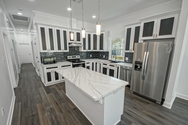 kitchen featuring sink, a center island, light stone countertops, pendant lighting, and appliances with stainless steel finishes