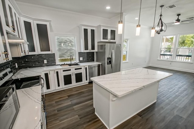 kitchen with stainless steel appliances, white cabinetry, a center island, and decorative light fixtures