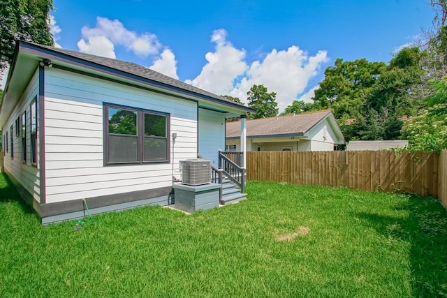 rear view of property featuring a yard and central AC unit