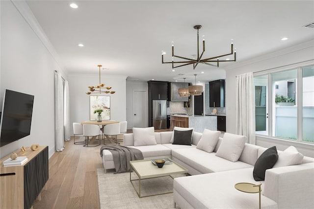 living room featuring ornamental molding, a notable chandelier, and light hardwood / wood-style floors