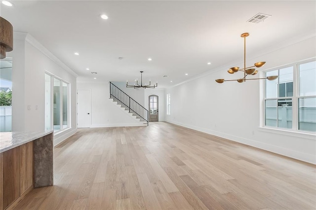 unfurnished living room featuring crown molding, an inviting chandelier, and light hardwood / wood-style flooring