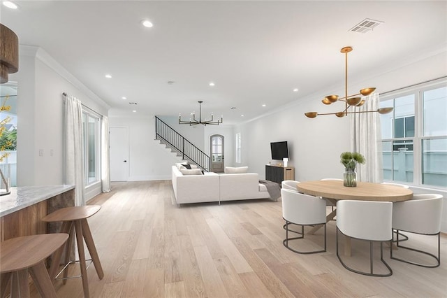 dining space featuring ornamental molding, a wealth of natural light, light wood-type flooring, and a notable chandelier