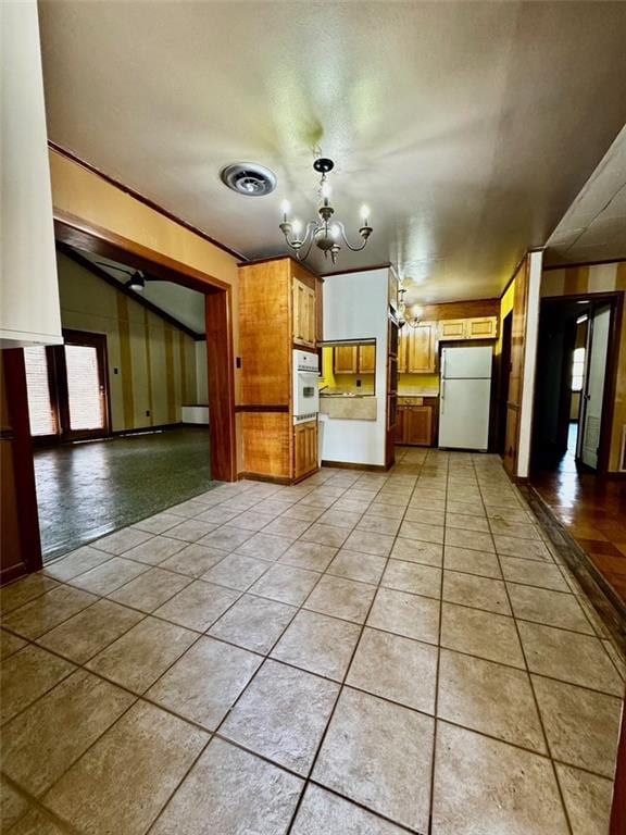 kitchen featuring white appliances, light tile patterned flooring, and a notable chandelier