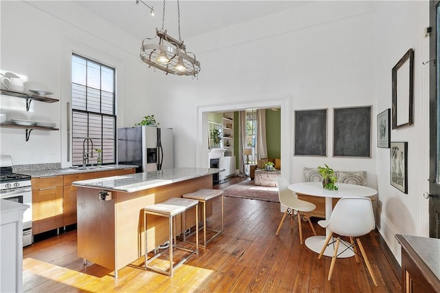 kitchen with light stone counters, light hardwood / wood-style floors, a breakfast bar, a kitchen island, and appliances with stainless steel finishes