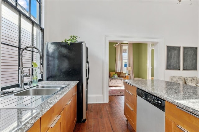 kitchen featuring sink, dark hardwood / wood-style flooring, light stone countertops, and appliances with stainless steel finishes