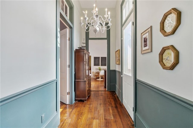 corridor featuring hardwood / wood-style floors, an inviting chandelier, and a towering ceiling