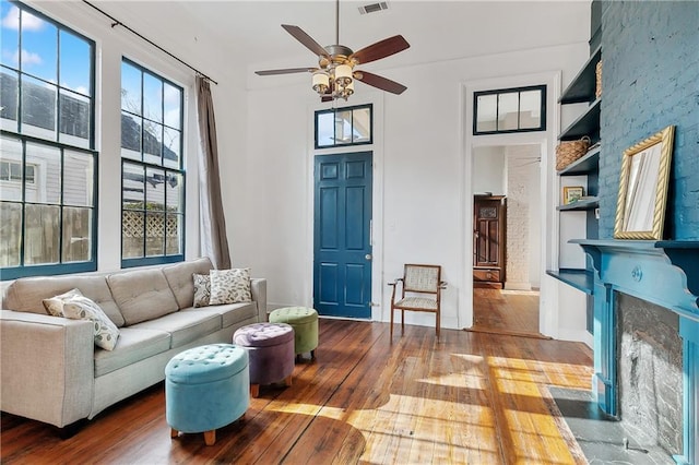 living room with ceiling fan, a premium fireplace, built in shelves, and wood-type flooring