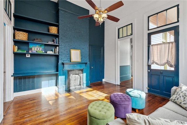 living room featuring built in shelves, ceiling fan, and hardwood / wood-style floors