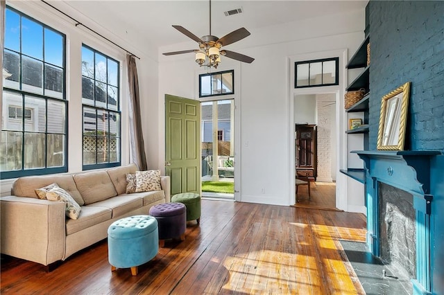 living room with dark hardwood / wood-style flooring, a fireplace, plenty of natural light, and built in features