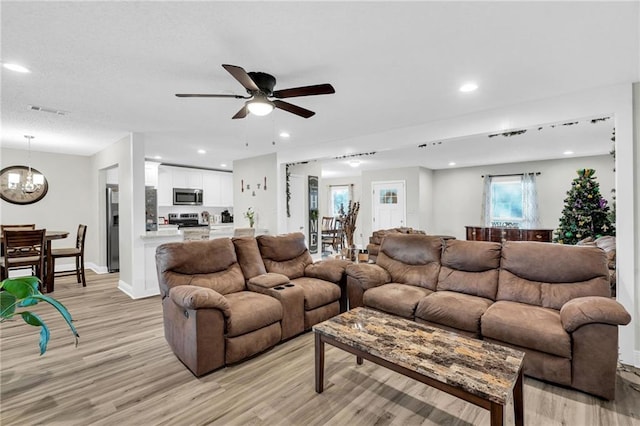 living room featuring light wood-type flooring and ceiling fan with notable chandelier