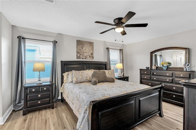 bedroom with a textured ceiling, ceiling fan, and light hardwood / wood-style flooring