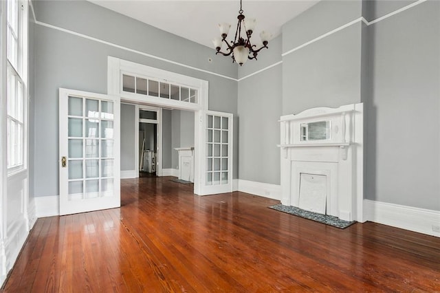 unfurnished dining area featuring french doors, wood-type flooring, and a notable chandelier