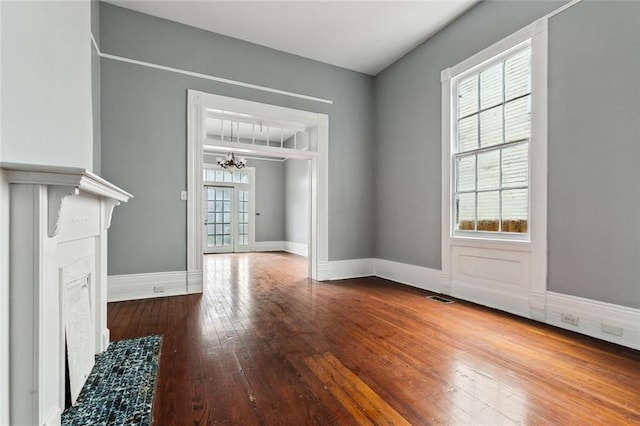 unfurnished living room with a notable chandelier and hardwood / wood-style floors